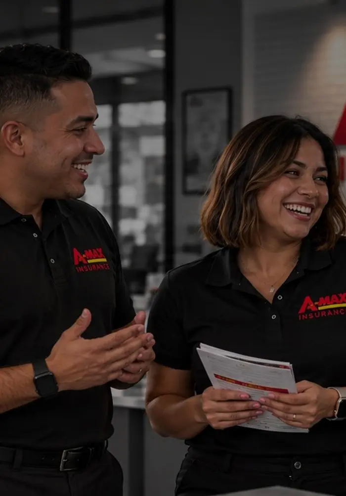 Three smiling A-MAX team members in branded polos talking together in an A-MAX office