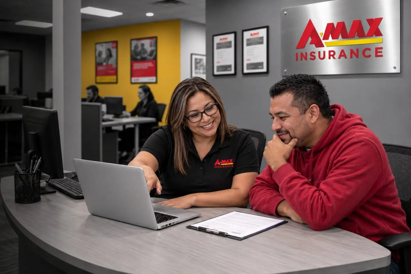 An A-MAX agent comparing quote options with a customer at an office desk