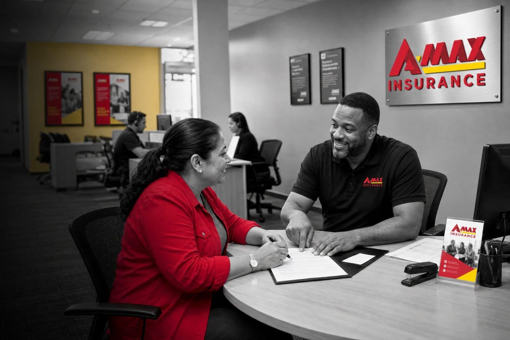 An A-MAX agent helping a customer sign paperwork at an office desk